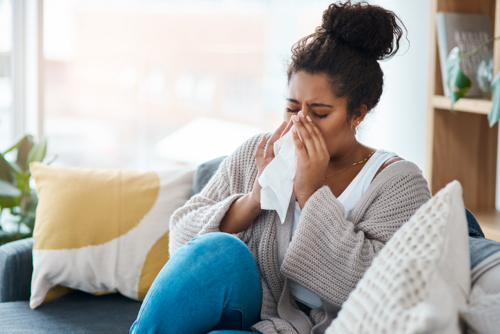 woman sitting on couch and sneezing