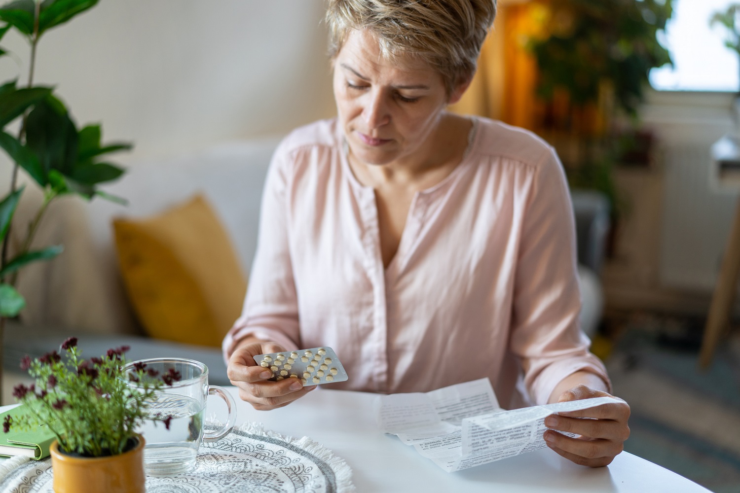 : Person holding a blister pack of pills and reviewing medication information