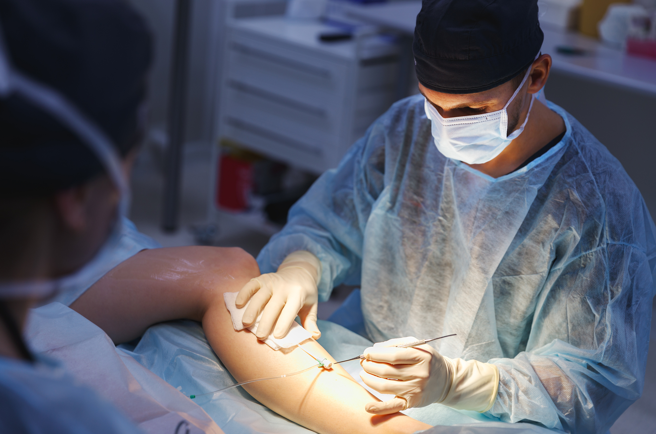 Surgeon performing laparoscopic vascular surgery on a leg
