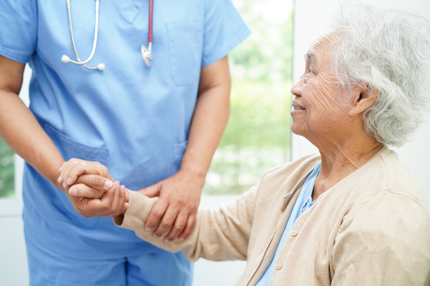 elderly woman holding hands with medical staff