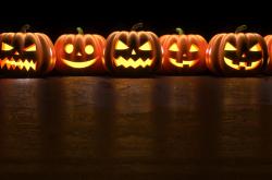 Many Halloween Pumpkin glowing faces in a row isolated on black background. 3D Rendering illustration