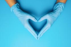 Gloved hands on a blue background forming a heart