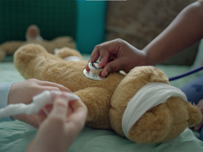 Little girl using a stethoscope on a teddy bear