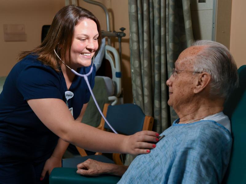 Smiling nurse using a stethoscope to listen to a senior man's chest
