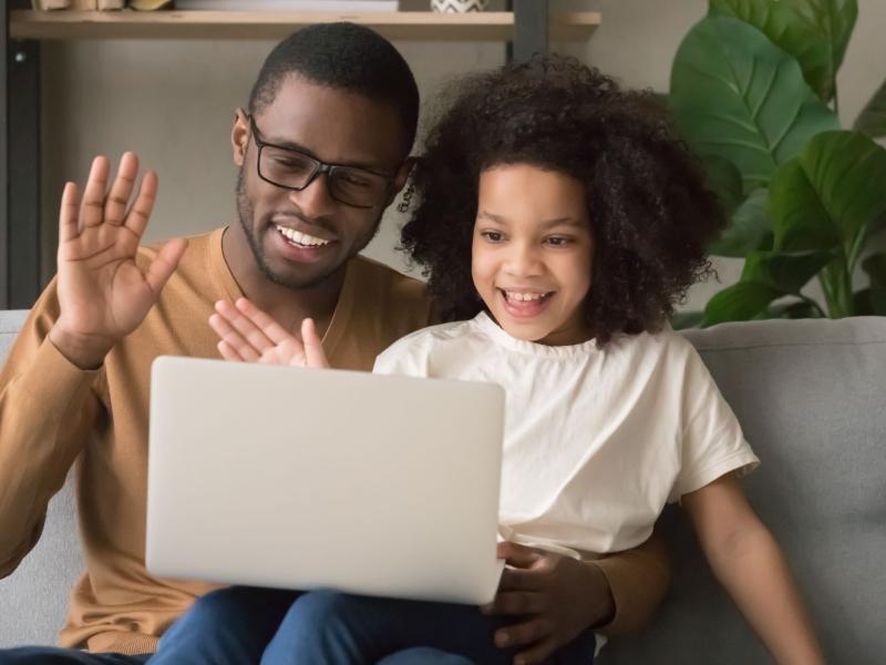 Father and daughter waving to a laptop screen