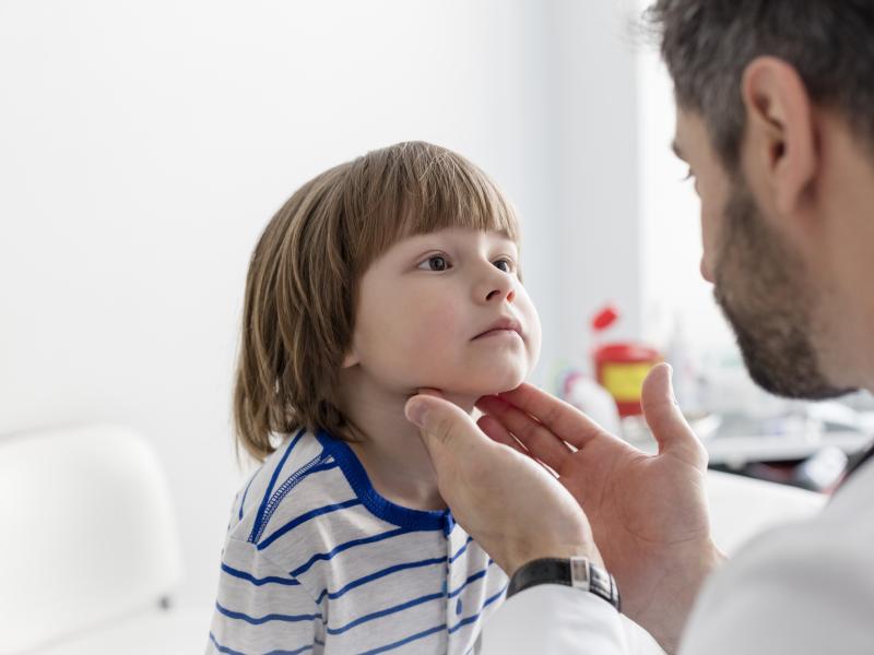 A doctor examining a child's tonsils with their hands
