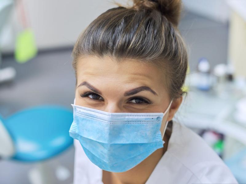 female dentist smiling behind medical mask