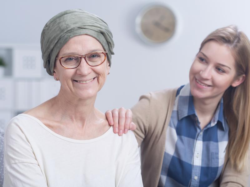 smiling woman with cancer being comforted by a smiling young woman