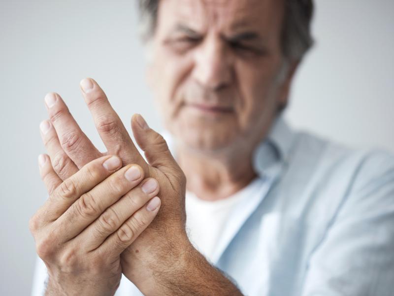 An older man cringing and holding his hand in pain