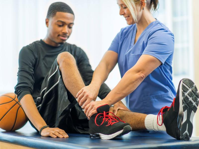 physician and male basketball player examining ankle