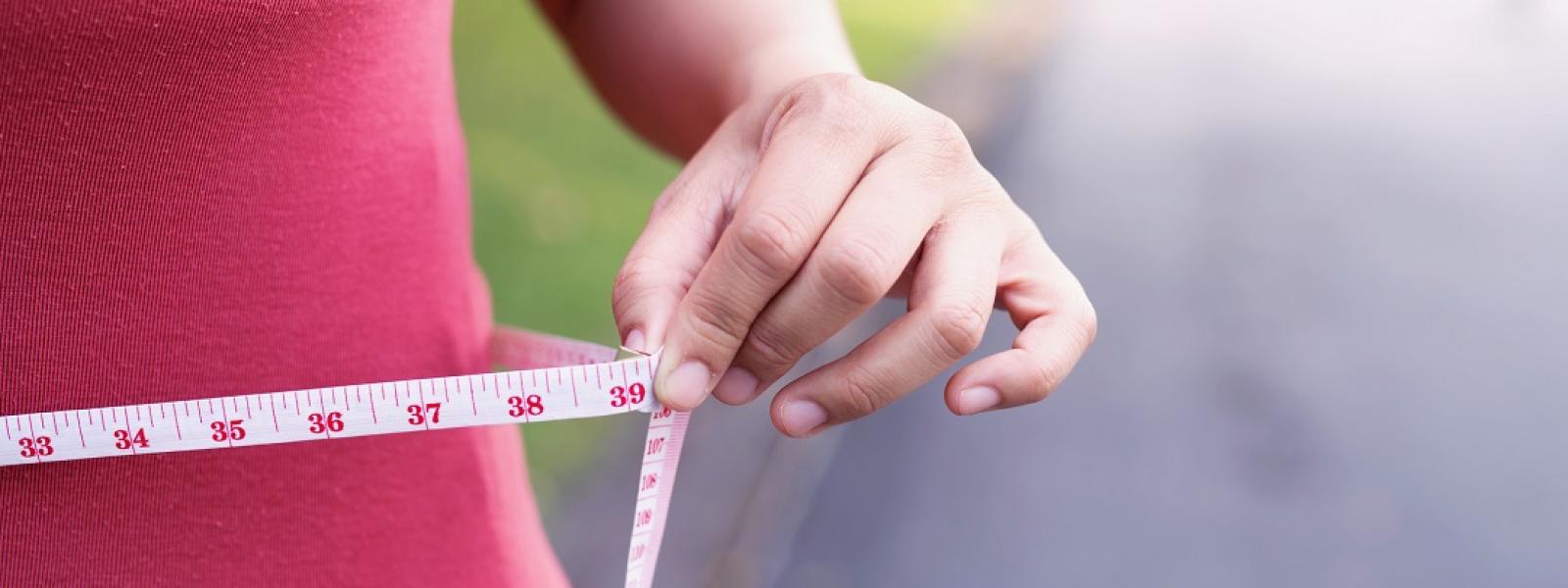 Woman measuring her waist after weight loss surgery