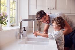 Parent teaching young kid to wash hands