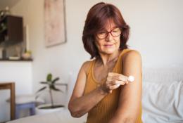 Woman putting bandage on her arm