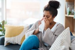 woman sitting on couch and sneezing