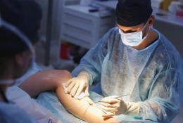 Surgeon performing laparoscopic vascular surgery on a leg