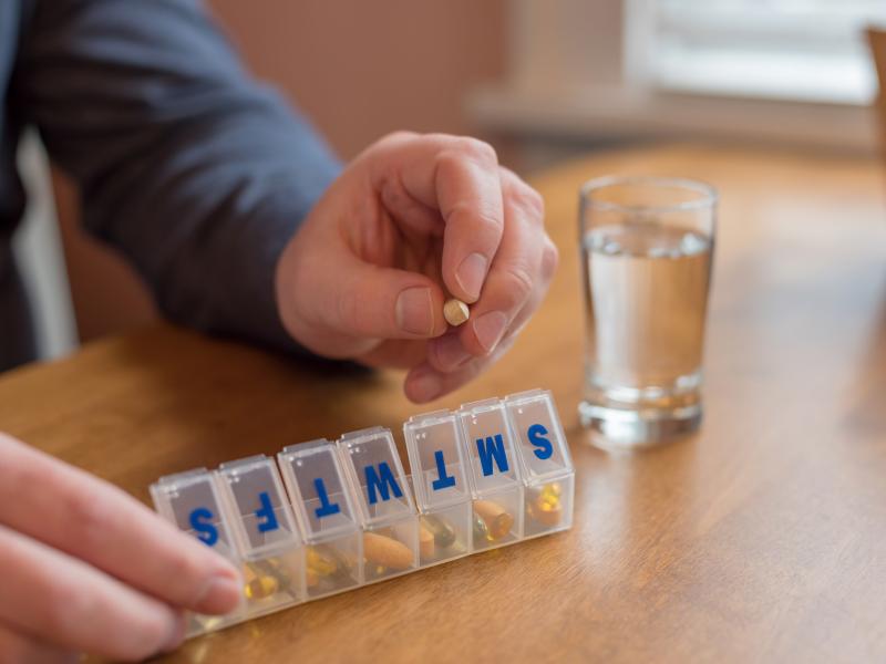 Man using a pill holder for daily meds, vitamins and supplements