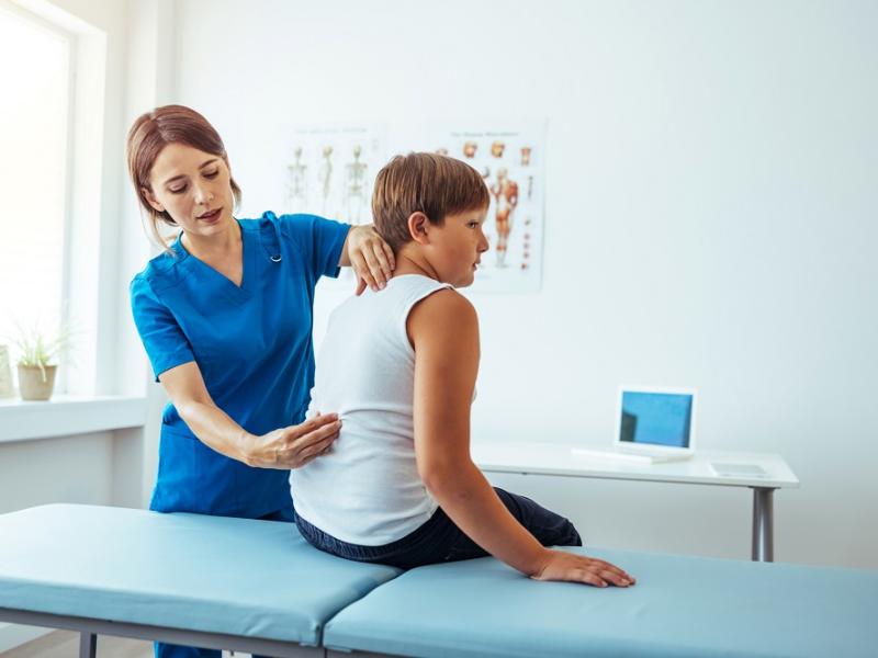 Nurse Checking a Child's Spine Development for Scoliosis