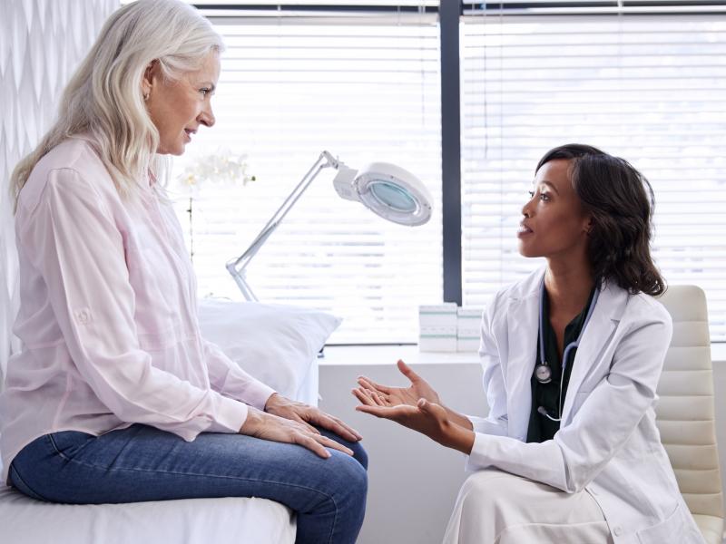 An older woman on a patient table talking with a doctor
