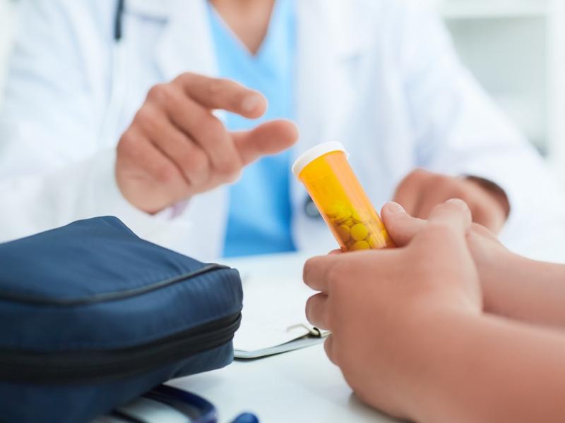 Male Doctor Hands a Pill Bottle to Patient