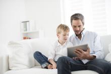 A man reading with his child on a couch