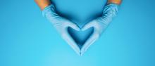 Gloved hands on a blue background forming a heart