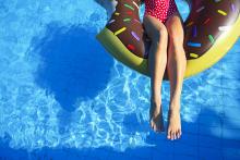 Young woman on inflatable mattress in the swimming pool. Summer vacation concept