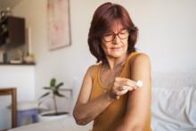 Woman putting bandage on her arm