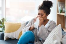 woman sitting on couch and sneezing