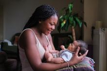 Young black woman holding her new born and smiling