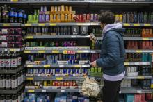 A man reading the nutrition label of an energy drink in a supermarket