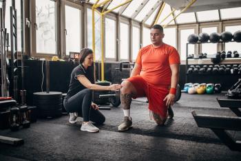 Female Physical Therapist working with overweight man
