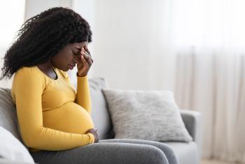 Young pregnant black woman suffering from headache or migraine, feeling sick, sitting on sofa at home, free space