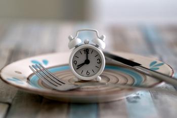 Table clock and fork on empty plate