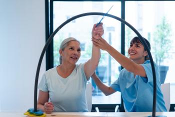 Therapist doing movement therapy with elderly woman patient