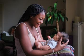 Young black woman holding her new born and smiling