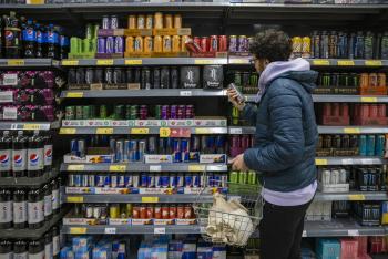 A man reading the nutrition label of an energy drink in a supermarket