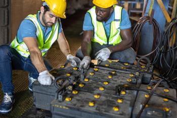 Engineers working charging old battery in train cabin