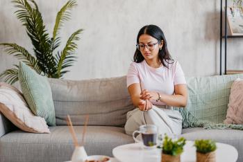 A woman scratching her arm while sitting on the sofa