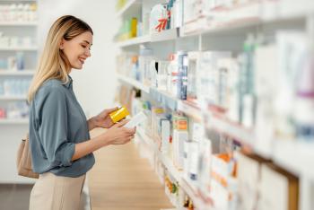 A woman peruses the shelf at a pharmacy, reading the label